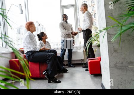 Multiracial colleagues talking and smiling while working in office Stock Photo