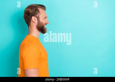 Side profile photo of satisfied positive guy with blond hairdo wear orange t-shirt look empty space isolated on teal color background Stock Photo