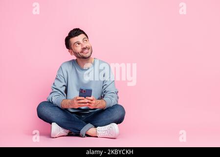 Full body photo of nice young man hold gadget hold smart phone look empty space wear stylish blue outfit isolated on pink color background Stock Photo
