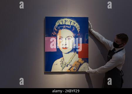 (EDITOR'S NOTE: Editorial use only) A staff member presents 'Queen Elizabeth II' from: Reigning Queens (Royal Edition) screenprint in colours with diamond dust, 1985, by Andy Warhol (estimated sale price ?100,000-150,000) during a press preview of 'Prints & Multiples: Modern to Pop' online sale at Christie's on September 09, 2020 in London, England. The sale, taking place from 10 - 22 September, will showcase classic modern and pop prints, including works from 20th century icons such as Henri Matisse, Pablo Picasso, Francis Bacon, David Hockney, Andy Warhol, Roy Lichtenstein and Keith Haring.  Stock Photo