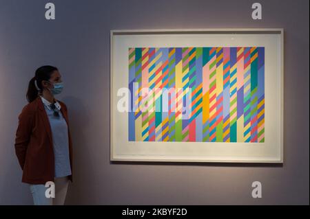 (EDITOR'S NOTE: Editorial use only) A staff member stands next to 'June', screenprint in colours, 1992-2002, by Bridget Riley (estimated sale price ?10,000-15,000) during a press preview at Christie's on September 09, 2020 in London, England. (Photo by WIktor Szymanowicz/NurPhoto) Stock Photo