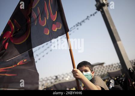 An Iranian boy wearing a protective face mask waves a religious flag while attending a protest gathering against the Charlie Hebdo French satirical weekly magazine which re-published a cartoon of the prophet Mohammad, in southern Tehran on September 10, 2020. (Photo by Morteza Nikoubazl/NurPhoto) Stock Photo