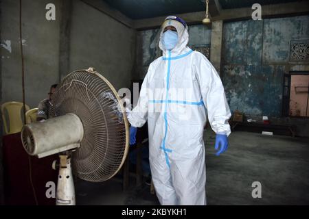 A health worker in personal protective equipment (PPE) stands in front of a fan while waiting for people to collect samples to conduct tests for the coronavirus disease (COVID-19), amid the spread of the disease in Nagaon district, in the northeastern state of Assam, India, September 12, 2020 (Photo by Anuwar Hazarika/NurPhoto) Stock Photo
