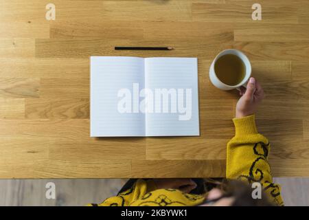 Open empty notebook and pencil, woman holding a mug with tea Stock Photo