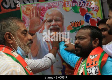 A supporter of India's Bharatiya Janata Party (BJP) symbolically holds a piece of Laddu ( Sweet) next to the portrait of Indian Prime Minister Narendra Modi during Modi's 70th birthday celebrations, in Kolkata, India, on September 17, 2020. (Photo by Debajyoti Chakraborty/NurPhoto) Stock Photo