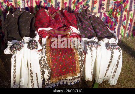 Hunedoara County, Romania, 2003. Different authentic traditional women costumes from the region of Padureni. The red colored clothing are worn by young women, while the white and grey/ black ones are specific for elderly women. Stock Photo