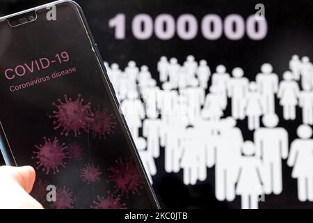 For illustrative purposes a woman holds a mobile phone with Covid-19 graphics against one million people graphics the death toll of Covid 19 deaths reaches the first million on September 26, 2020. (Photo Illustration by Dominika Zarzycka/NurPhoto) Stock Photo