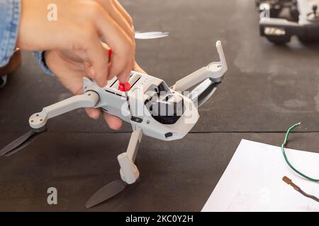 Close up view of unrecognizable man hands repairing small drone with screwdriver in hands Stock Photo