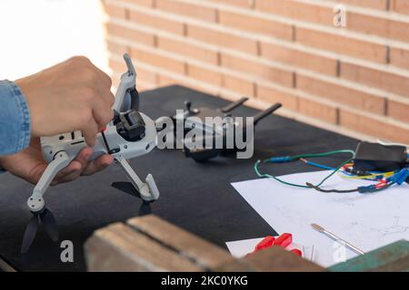 Professional unrecognizable mechanic repairing small drone with screwdriver on table with different tools Stock Photo