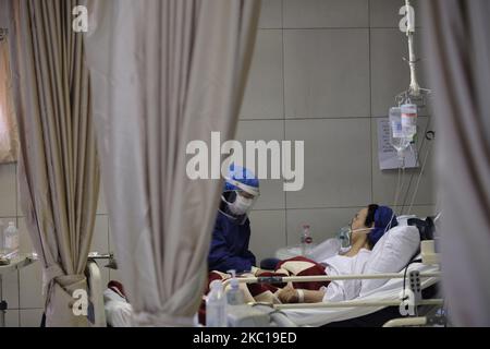 An Iranian medical personnel wearing a protective suit takes care of a woman who has infected by the new coronavirus disease in a COVID-19 section of a hospital in southern Tehran on October 6, 2020. Iranian health officials warn that Tehran has crossed the red line and the medical staff of hospitals will face problems and will not be able to control the new coronavirus disease (COVID-19) outbreak in the country, if people do not follow health protocols. (Photo by Morteza Nikoubazl/NurPhoto) Stock Photo