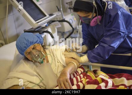 An Iranian medical personnel wearing a protective suit injects medicine into an elderly woman who has infected by the new coronavirus disease in a COVID-19 section of a hospital in southern Tehran on October 6, 2020. Iranian health officials warn that Tehran has crossed the red line and the medical staff of hospitals will face problems and will not be able to control the new coronavirus disease (COVID-19) outbreak in the country, if people do not follow health protocols. (Photo by Morteza Nikoubazl/NurPhoto) Stock Photo