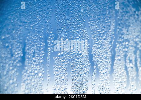 Texture of misted glass in winter. Frozen drops of water in sun on window. Dawn outside window. Abstract background. Selective focus. Stock Photo
