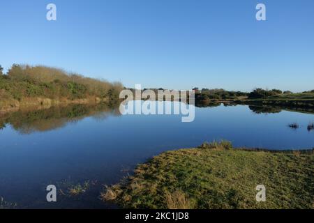 A bright winter day with mirror smooth water suirface on the lakes formed in the nature reserve on the disused airfield at Greenham Common Airbase nea Stock Photo