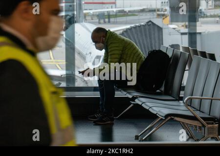 Passengers with facemask sitting infront of the window with aircraft in the background. Passengers wearing facemasks, face shields, gloves and other safety measures are seen in the airport terminal, at the F Gates area of Vienna International Airport VIE LOWW - Flughafen Wien-Schwechat serving the Austrian Capital but also Bratislava as it is 55km away from the Slovak city during the Covid-19 Coronavirus pandemic era. There is a second wave coming while cases are increasing, facemask become mandatory, social distancing measures and disinfecting hand sanitizer are everywhere while new lockdowns Stock Photo