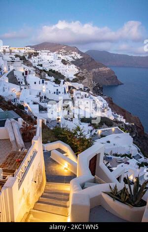 Magic hour in the dusk just after the sunset in the famous Oia Village with blue dome churches, windmills and whitewashed with traditional architecture buildings standing on the edge of the cliff in Santorini Volcanic Island in Greece. The Mediterranean Island in the Aegean is an inhabited volcano, one of the most famous travel destinations in the world especially for couples and honeymoon as there is an incredible sunset every day with an amazing view of the caldera. In 2020 Santorini as more Greek islands tried to attract tourists despite the low passenger traffic restrictions, quarantine an Stock Photo