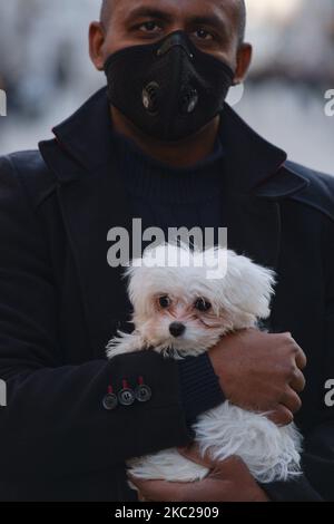 A man in a protective face mask carries a small dog in Krakow's city center. Today, the Ministry of Health reported 9,291 new cases of COVID-19 in Poland, including a record number of 1,486 in the Malopolskie Voivodeship. Moreover, every third person diagnosed with COVID-19 in the Malopolskie Voivodeship lives in Krakow. On Tuesday, October 20, 2020, in Krakow, Poland. (Photo by Artur Widak/NurPhoto) Stock Photo