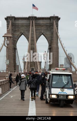 The police and people on Brooklyn Bridge in New York City in the United States as seen during a cloudy day with tourists and locals on it. The famous bridge, a landmark for NYC and the United States of America is a hybrid cable stayed suspension bridge spanning the East River between the boroughs of Manhattan and Brooklyn. The historical NY landmark bridge was built between 1869 and 1883. New York, USA on February 13, 2020 (Photo by Nicolas Economou/NurPhoto) Stock Photo