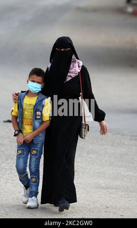 A Palestinian woman walks alongside her child, in Rafah town in the southern Gaza Strip on October 24, 2020. (Photo by Majdi Fathi/NurPhoto) Stock Photo