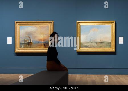 (EDITORIAL USE ONLY) A gallery staff member poses next to 'The Fighting Temeraire, tugged to her last berth to be broken up', 1838 (L) and 'Steamer and Lightship; a study for ‘The Fighting Temeraire’ c.1838–9 (R) by JMW Turner (1775-1851) during a photocall to promote opening of 'Turner's Modern World' exhibition at Tate Britain (28 October 2020 - 7 March 2021) dedicated to Britain’s greatest landscape painter, on 26 October 2020 in London, England. (Photo by WIktor Szymanowicz/NurPhoto) Stock Photo
