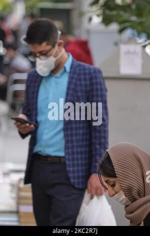 An Iranian woman and a man wearing protective face mask to prevent themselves of infection by the new coronavirus disease (COVID-19) in Tehran’s business district on October 26, 2020. (Photo by Morteza Nikoubazl/NurPhoto) Stock Photo