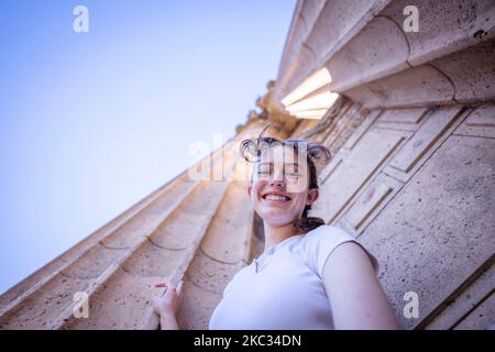 Low Angle Shot of Teenage Female Between Two Roman Columns in San Francisco Stock Photo