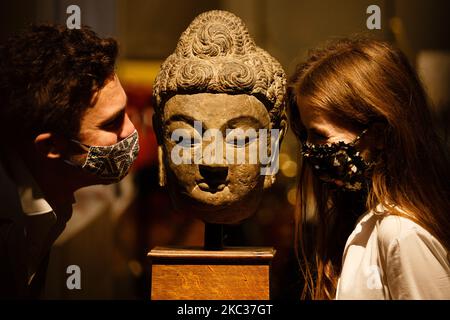 Members of staff poses with a grey limestone Buddha head from the 7th century Tang Dynasty (estimated GBP80,000-120,000) in the fine Chinese art section of the Asian Art Week collection at Bonhams auction house on New Bond Street in London, England, on November 2, 2020. The sale takes place on November 5. (Photo by David Cliff/NurPhoto) Stock Photo