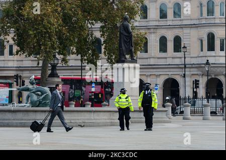 A man with a suitcase walks past police officers patrolling Trafalgar Square as England enters a four-week lockdown to tackle the spread of coronavirus, on 05 November, 2020 in London, England. From today until 2 December people will are asked to stay at home where possible, all nonessential shops, restaurants, pubs and leisure facilities close, international travel is banned except for work, but schools, colleges and universities remain open. (Photo by WIktor Szymanowicz/NurPhoto) Stock Photo