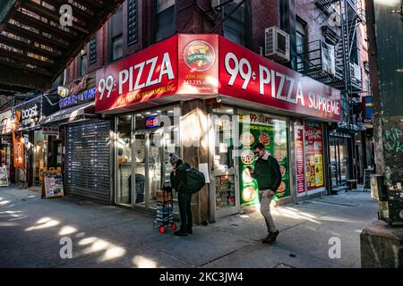 A man passing in front of 99c dolar slice pizza holding his phone and walking. Daily life view of the road and street under the subway railroad air-bridge metal construction of M, J and Z lines near Marcy Ave station, with restaurants, shops, the famous dollar slice pizza, traffic with cars and trucks and with sidewalks in Broadway street in Brooklyn, New York City. Brooklyn is the most populous county in the state of New York and the second-most densely populated in the United States. Brooklyn, NY, USA on 13 February 2020. (Photo by Nicolas Economou/NurPhoto) Stock Photo