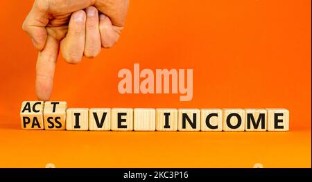 Passive or active income symbol. Businessman turns wooden cubes and ...