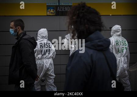 In the photo some boys in white overalls, similar to those used by doctors and nurses in covid wards, with the words 'Rise up!' on the back they post posters against Azienda Zero on the external walls of the offending company. Padua, November 13, 2020, Italy. The social centers of the North East, and in particular the Padua delegation, gathered under the headquarters of Azienda Zero in Padua to protest against the lack of protection against doctors and nurses involved in the Covid19 pandemic. Here they posted placards with protest slogans and then went peacefully to the Hospital of Padua escor Stock Photo