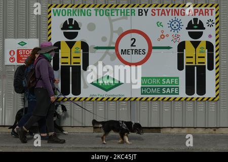 People walk their dogs next to a Work Safety rules board in Dublin city center. On Tuesday, November 17, 2020, in Dublin, Ireland. (Photo by Artur Widak/NurPhoto) Stock Photo