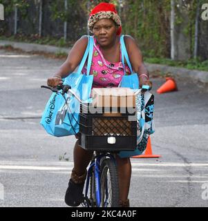 A woman on a bicycle carries food donated by the Second Harvest Food Bank of Central Florida and the City of Orlando at a food distribution event at Jones High School on November 20, 2020 in Orlando, Florida. With the approach of Thanksgiving, thousands of families in the Orlando area are in need of food assistance due to massive layoffs in local theme parks and the tourist industry. (Photo by Paul Hennessy/NurPhoto) Stock Photo