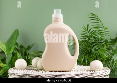 Natural laundry detergent mockup. Washing detergent concept with bottles of washing gel or fabric softener on a white laundry basket on a green backgr Stock Photo
