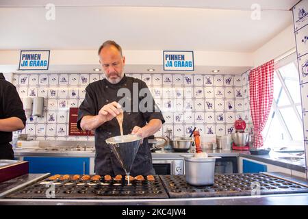 ? pastry chef is making Dutch pancakes. Daily life in Volendam traditional fishing village with Dutch architecture in North Holland near Amsterdam in The Netherlands. Volendam has a harbor and is a popular destination and tourist attraction in the country. There are old fishing boats, traditional clothing of locals, ferry ride to Marken, museums, cheese factroy, cafe and souvenir shops at the waterfront and a little beach. There are houses along the shore and a marina nearby for tourists and locals as visitors so tourism is the main income for the community. Volendam has been featured in many  Stock Photo