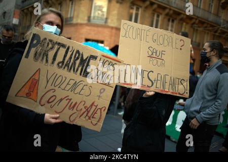 Two woman hold placards: 'Carrying a weapon out of service: domestic violences' (Right) and 'Global security ? Except for women and children' (Left). More than 5000 protesters demonstrated for the 4th time for a protest against the so-called 'Global Security Law' bill promoted by French President Macron and his majority. The 'Global Security Law' bill will also forbid anyone to photograph or film police members if not flouted : transgressors could be condemned up to one year in jail and a €45.000 fine. The bill also plans to generalize facial recognition in pubic spaces as in China.The French  Stock Photo