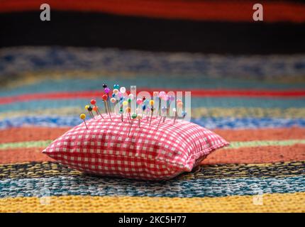 Pin cushion with colorful pinheads on soft and warm knitted background, selective focus Stock Photo