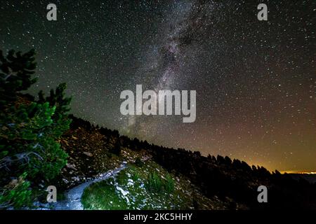 Milky Way captured with long exposure photography technique. Milkyway is the visible part of our galaxy that contains our Solar System as seen during the night from Olympus Mountain the mythical mountain in Ancient Greek culture, between Petrostrouga refuge and Skourta peak at the hiking trail above 2000m above the sea level in Greece during the night. Night landscape with trees, forest, summits with colorful Milky Way sky dome, cloudless sky at mountains with the starry sky with hills at summer with the beautiful Universe and Space background. Olympus Mountain National Park, Greece - October  Stock Photo