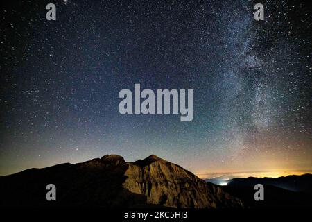 Milky Way captured with long exposure photography technique. Milkyway is the visible part of our galaxy that contains our Solar System as seen during the night from Olympus Mountain the mythical mountain in Ancient Greek culture, between Petrostrouga refuge and Skourta peak at the hiking trail above 2000m above the sea level in Greece during the night. Night landscape with trees, forest, summits with colorful Milky Way sky dome, cloudless sky at mountains with the starry sky with hills at summer with the beautiful Universe and Space background. Olympus Mountain National Park, Greece - October  Stock Photo
