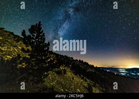 Milky Way captured with long exposure photography technique. Milkyway is the visible part of our galaxy that contains our Solar System as seen during the night from Olympus Mountain the mythical mountain in Ancient Greek culture, between Petrostrouga refuge and Skourta peak at the hiking trail above 2000m above the sea level in Greece during the night. Night landscape with trees, forest, summits with colorful Milky Way sky dome, cloudless sky at mountains with the starry sky with hills at summer with the beautiful Universe and Space background. Olympus Mountain National Park, Greece - October  Stock Photo