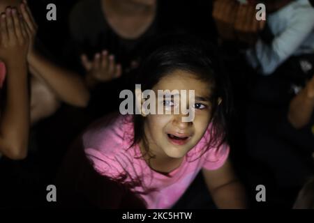 A little girl with tears on her eyes is praying. Hundreds of women and girls are seen praying on the road after the sunset, at the makeshift tent site that was built roadside after the fire of Moria refugee camp and hotspot when some refugees were tested positive in Covid-19 Coronavirus and denied the quarantine as a safety measure against the spread of the pandemic. The Muslim pray of this large homeless group of asylum seekers took place on the street near a grocery store, outside of Mytilene town, near Kara Tepe new temporary camp location. They prayed with their hands risen, an Islamic han Stock Photo
