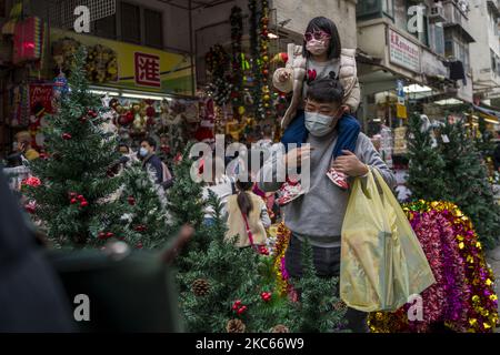 A Father is seen holding up his daughter as they browse Christmas Decorations on December 20, 2020 in Hong Kong, China. Hong Kong today reported over 74 new Covid-19 Cases as the city is facing a four wave of Covid-19, the government has banned dinning in after 6pm. (Photo by Vernon Yuen/NurPhoto)