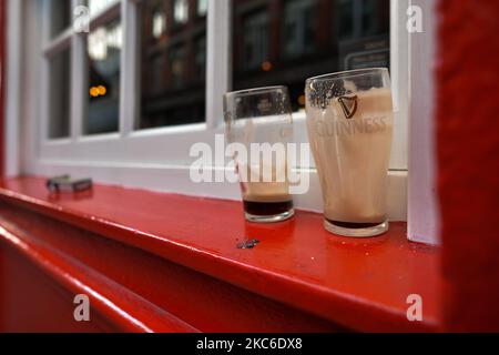 Two empty pints of Guinness seen in a window outside a closed pub in Dublin city center. From today 3pm, all restaurants and pubs have closed. Hairdressers, barbers, beauticians, cinemas and galleries will also shut by the end of the day. On Thursday, December 24, 2020, in Dublin, Ireland. (Photo by Artur Widak/NurPhoto) Stock Photo