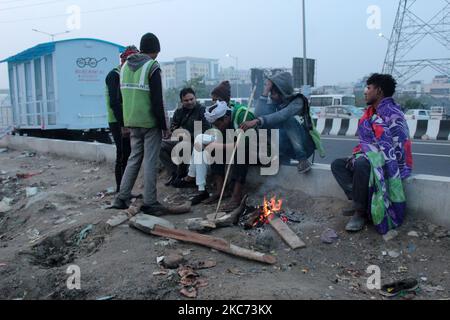 Sanitation workers of Ghaziabad warm themselves around a fire on a cold evening at the site of a protest against the newly passed farm bills, at Delhi-Uttar Pradesh border near Ghazipur on the outskirts of New Delhi, India on January 7, 2021. (Photo by Mayank Makhija/NurPhoto) Stock Photo