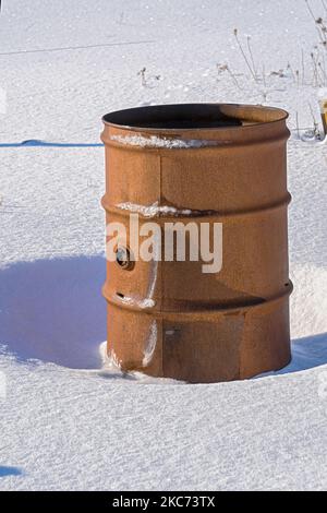 Brown old rusty oil barrel in the snow. Stock Photo