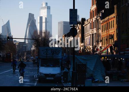 Traffic passes beside market stalls in Whitechapel as the towers of the Leadenhall Building (L), 30 St Mary Axe ('The Gherkin', C), and 22 Bishopsgate (R) stand in winter sunlight in the City of London financial district in London, England, on January 9, 2021. England began a third national lockdown on Tuesday in a bid to stem coronavirus transmission across the country. In the capital, Mayor of London Sadiq Khan yesterday declared a 'major incident' for the city over coronavirus pressures, warning that hospitals could soon be overwhelmed with patients with covid-19. (Photo by David Cliff/NurP Stock Photo