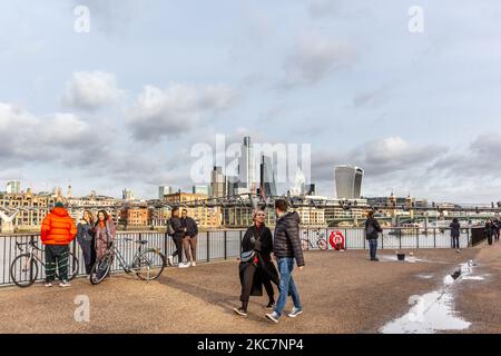 Passers-by are seen walking on Sunday sunny afternoon in Southbank embankment by the Thames River with the City in the background as the UK's government introduced strict Coronavirus restrictions earlier this month due to sharp increase in numbers of Covid-19 cases in the UK - London, England on January 17, 2021. Under the new regulations people are only allowed to take short walks locally within their limited social bubble as an exception for Stay at Home policy. (Photo by Dominika Zarzycka/NurPhoto) Stock Photo
