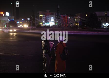 An Iranian man and a woman wearing protective face masks stand on a corner of a square while power blackouts in northern Tehran at night on January 21, 2020. (Photo by Morteza Nikoubazl/NurPhoto) Stock Photo