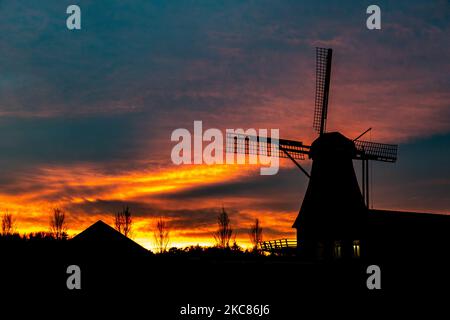 A traditional Dutch windmill as seen around sunset time at the sweet spot called magic hour at the dusk during a cold winter day, where the colorful clear sky is mixing with the clouds. The windmill, a tourism attraction and symbol for the country, is located in the outskirts of Veldhoven, near the city of Eindhoven in North Brabant region. The specific mill is a bakery and cafe, the Oerse Mill Baker. Veldhoven, the Netherlands on January 25, 2021 (Photo by Nicolas Economou/NurPhoto) Stock Photo
