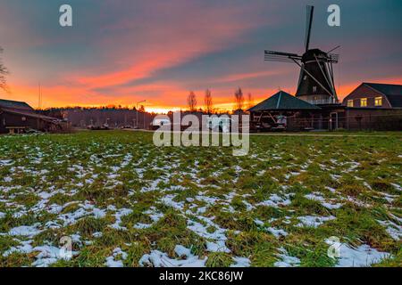 HDR - High Dynamic Range picture of a traditional Dutch windmill with snow on the grass as seen around sunset time at the sweet spot called magic hour at the dusk during a cold winter day, where the colorful clear sky is mixing with the clouds. The windmill, a tourism attraction and symbol for the country, is located in the outskirts of Veldhoven, near the city of Eindhoven in North Brabant region. The specific mill is a bakery and cafe, the Oerse Mill Baker. Veldhoven, the Netherlands on January 25, 2021 (Photo by Nicolas Economou/NurPhoto) Stock Photo