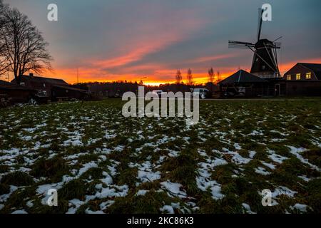 HDR - High Dynamic Range picture of a traditional Dutch windmill with snow on the grass as seen around sunset time at the sweet spot called magic hour at the dusk during a cold winter day, where the colorful clear sky is mixing with the clouds. The windmill, a tourism attraction and symbol for the country, is located in the outskirts of Veldhoven, near the city of Eindhoven in North Brabant region. The specific mill is a bakery and cafe, the Oerse Mill Baker. Veldhoven, the Netherlands on January 25, 2021 (Photo by Nicolas Economou/NurPhoto) Stock Photo